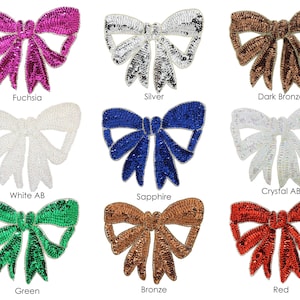 May include: Assortment of nine sequined bow appliques in various colors, including fuchsia, silver, dark bronze, white AB, sapphire, crystal AB, green, bronze, and red.
