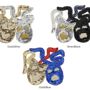 May include: Three pairs of fabric appliques in the shape of two masks, one smiling and one frowning. The masks are made of sequins in gold and silver, silver and black, and gold and blue.