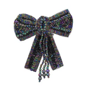 Puede incluir: Un lazo negro iridiscente con flecos de cuentas. El lazo está hecho de lentejuelas y cuentas.