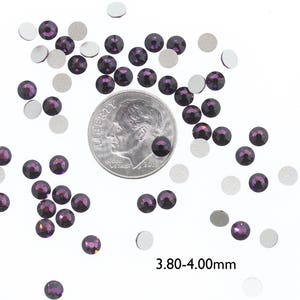 May include: A scattering of small, dark purple rhinestones, some with silver backing, next to a US dime for size comparison. The rhinestones are approximately 3.80-4.00 mm in size.