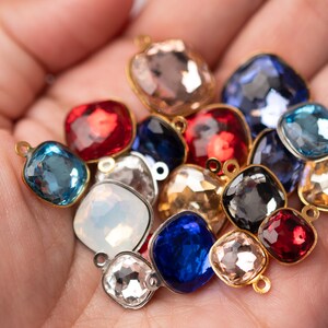May include: Assortment of colorful square-shaped glass beads with gold-toned metal loops. The beads are in various shades of blue, red, pink, and clear.
