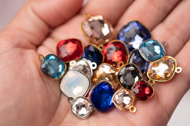 May include: Assortment of colorful square-shaped glass beads with gold-toned metal loops. The beads are in various shades of blue, red, pink, and clear.