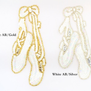 May include: Two pairs of white ballet shoes with iridescent sequins and a gold or silver bow.  White AB/Gold and White AB/Silver.