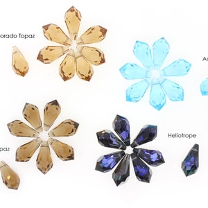 May include: Assortment of crystal teardrop pendants in four colours: light Colorado topaz, smoke topaz, aqua, and heliotrope. Each colour is arranged in a starburst pattern with a single pendant below.