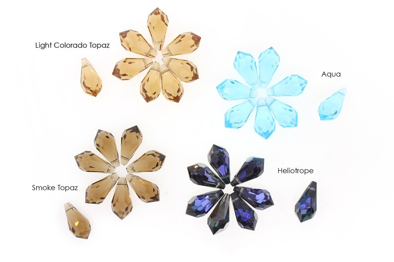 May include: Assortment of crystal teardrop pendants in four colours: light Colorado topaz, smoke topaz, aqua, and heliotrope. Each colour is arranged in a starburst pattern with a single pendant below.