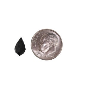 May include: A black faceted teardrop-shaped crystal pendant, approximately the size of a US dime.