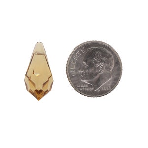 May include: A clear amber teardrop-shaped crystal prism pendant, approximately the size of a UK ten pence coin.