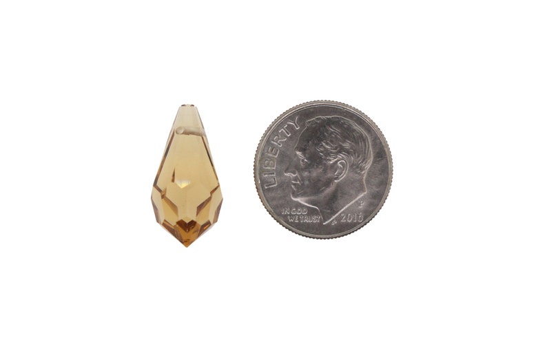May include: A clear amber teardrop-shaped crystal prism pendant, approximately the size of a UK ten pence coin.