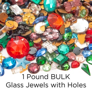 May include: A large assortment of colorful glass jewels with holes, in various shapes and sizes. The jewels are a mix of red, green, blue, purple, and clear glass. 1 Pound BULK Glass Jewels with Holes