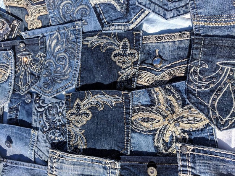 Puede incluir: Un mosaico de tela vaquera con varios dise&ntilde;os bordados en hilo plateado y dorado. La tela es una mezcla de tonos azules claros y oscuros.