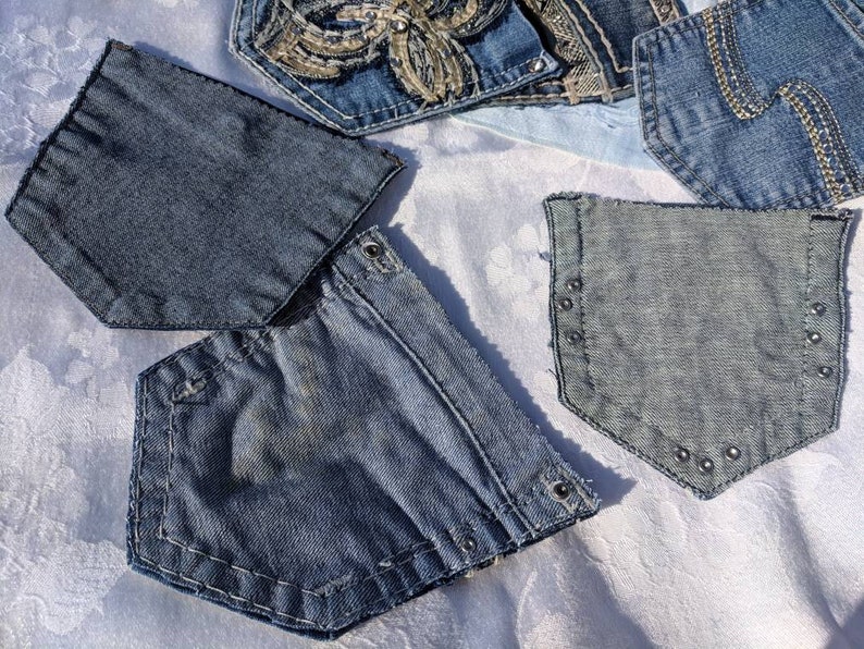 Puede incluir: Cuatro bolsillos de mezclilla con diferentes costuras y adornos. Los bolsillos son todos azules y tienen un aspecto desgastado.