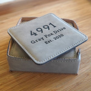 May include: Gray leather coaster set with the text "4991 Gray Fox Drive Est. 2020" engraved on the top coaster.
