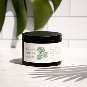 May include: Black candle jar with a white label that reads "Thank you for helping me grow." The label also features a green and white illustration of a monstera leaf.