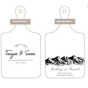 May include: Two white cutting boards with black mountain range illustrations and text. The first board says "Tonya & Sam" and "Mountain Ridge, NC Est. 2025". The second board says "Aubrey & Mark" and "May 24th, 2025 Colorado Springs".