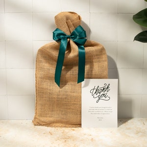 May include: A burlap gift bag tied with a teal satin ribbon and a thank you card. The card says "Thank you" in cursive and includes a message of appreciation.