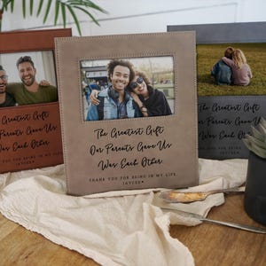 May include: Three personalized photo frames in brown, tan, and gray. Each frame has a rectangular photo opening and includes the text "The Greatest Gift Our Parents Gave Us Was Each Other." The frames are displayed on a light-colored surface.