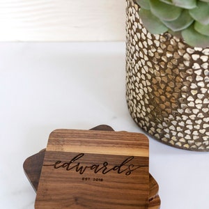 May include: Set of four wooden coasters with a natural wood finish. The top coaster features the engraved text "edwards est. 2018".