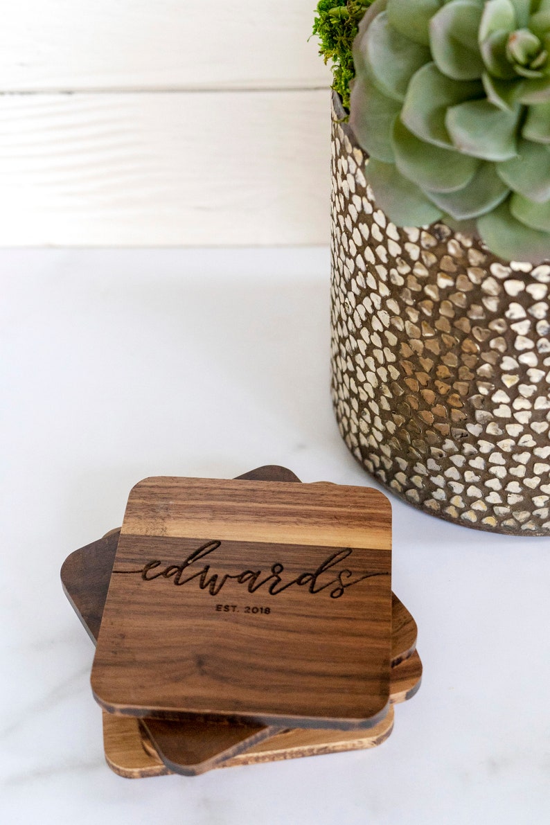 May include: Set of four wooden coasters with a natural wood finish. The top coaster features the engraved text "edwards est. 2018".