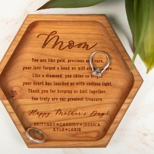 May include: A hexagonal wooden tray with a heartfelt message engraved on it, reading "Mom You are like gold, precious as rare. your love forged a bond we will always share. Like a diamond, you shine so bright your heart has touched us with endless light. Thank you for keeping us knit together. You truly are our greatest treasure. Happy Mother's Day! BRITTNEY CASSIDY JESSICA KYLE LEXIE".