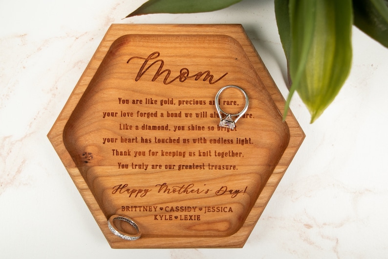 May include: A hexagonal wooden tray with a heartfelt message engraved on it, reading "Mom You are like gold, precious as rare. your love forged a bond we will always share. Like a diamond, you shine so bright your heart has touched us with endless light. Thank you for keeping us knit together. You truly are our greatest treasure. Happy Mother's Day! BRITTNEY CASSIDY JESSICA KYLE LEXIE".