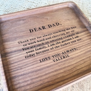 May include: A wooden tray with a personalized message engraved on the surface. The message reads "Dear Dad, Thank you for always teaching me how to work hard and cheering me on. You are such an amazing example to your family, I am the person I am today because of the father you are. Love you always, Valerie."