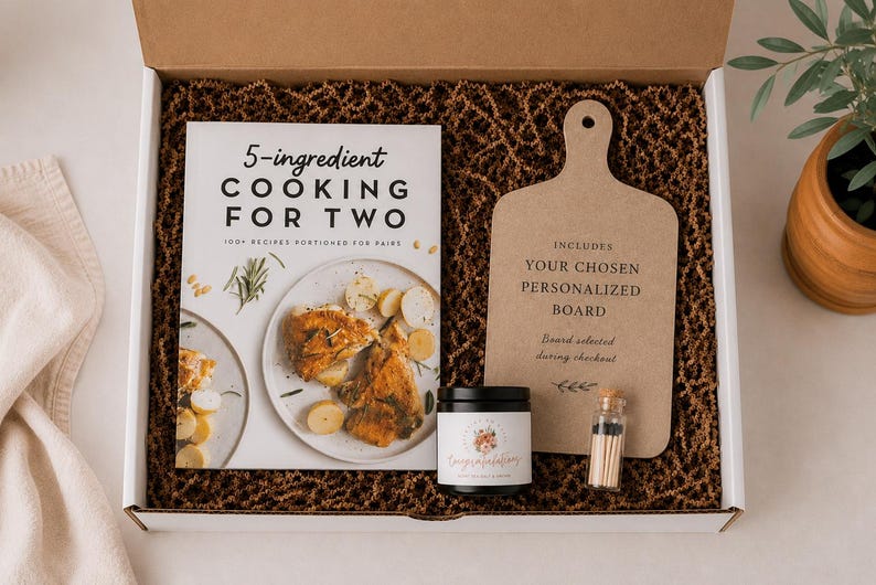 a gift box containing a cookbook, a wooden cutting board, a candle, and a small jar of spices.
