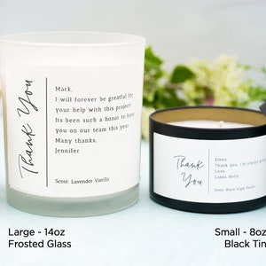 May include: Two candles, one in a frosted glass jar and one in a black tin, both with the text "Thank You" and a personalized message. The frosted glass candle is 14 ounces and the black tin candle is 8 ounces.