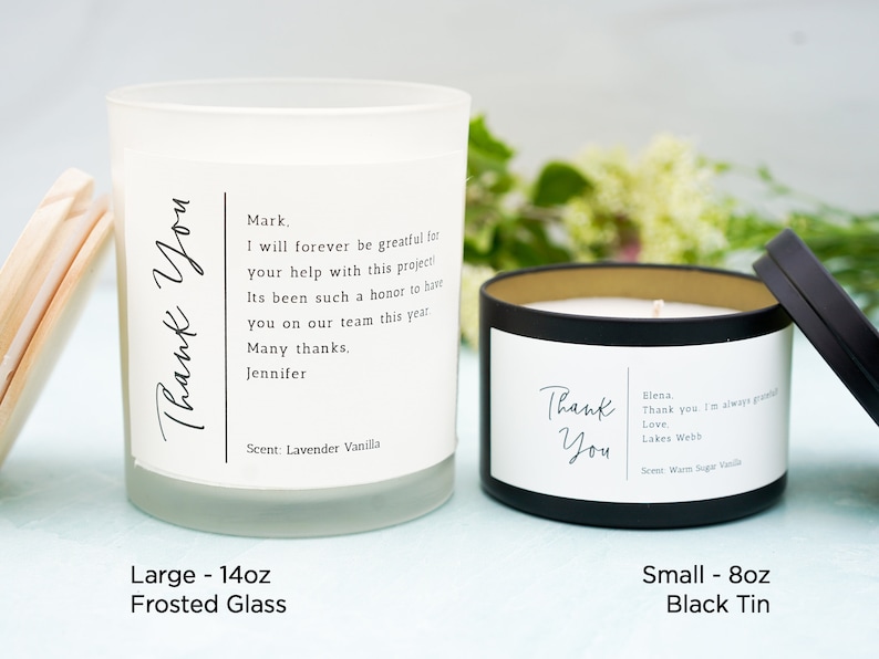 May include: Two candles, one in a frosted glass jar and one in a black tin, both with the text "Thank You" and a personalized message. The frosted glass candle is 14 ounces and the black tin candle is 8 ounces.
