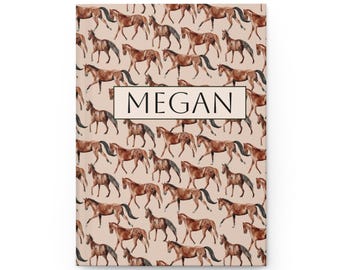 Può includere: Un diario con copertina rigida chiuso, con un motivo ripetuto di cavalli marroni su sfondo beige chiaro. Il nome "MEGAN" è stampato in un riquadro sulla copertina. Il diario è nuovo.