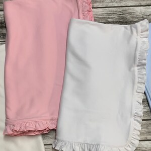 May include: Two baby blankets with ruffled edges. One is pink and the other is white.