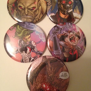 May include: Five circular pin badges featuring comic book characters. The badges depict a stern-faced character, Star-Lord, Gamora, Rocket Raccoon, and Groot with the text "I AM GROOT."