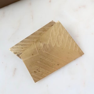 May include: Two gold-colored metal coasters with a geometric pattern. The coasters are stacked on top of each other.