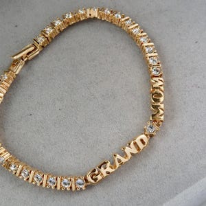 May include: Gold bracelet with clear rhinestones spelling out "GRANDMOM".