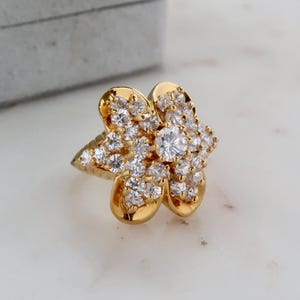 May include: A gold ring with a flower design set with clear cubic zirconia stones.