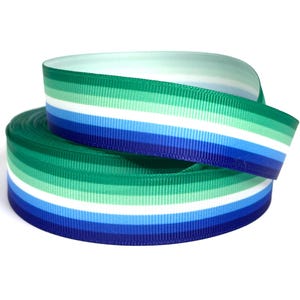 Peut inclure: Une bobine de ruban gros-grain présentant un motif à rayures horizontales dans des tons de vert foncé, vert clair, blanc, bleu clair et bleu foncé. Le ruban est enroulé en une bobine circulaire, affichant une texture côtelée uniforme.