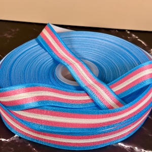 May include: A roll of blue, pink and white striped ribbon. The ribbon is satin and has a subtle sheen.