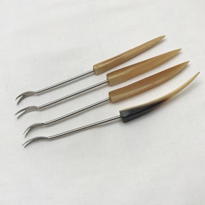 May include: Set of four small, silver, two-pronged forks with brown and beige horn handles.