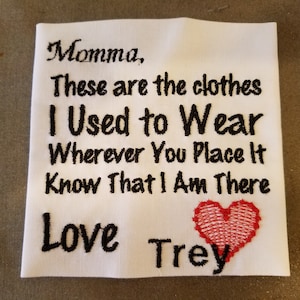 May include: White fabric square with black embroidered text that reads "Momma, These are the clothes I Used to Wear Wherever You Place It Know That I Am There Love Trey" and a red embroidered heart.