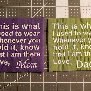 May include: Two purple and green fabric squares with white embroidered text. The text reads "This is what I used to wear Whenever you hold it, know that I am there Love, Mom" and "This is what I used to wear Whenever you hold it, know that I am there Love, Dad".