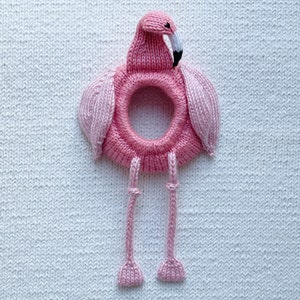 May include: Pink knitted flamingo toy with a ring in the middle and long legs.