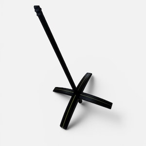 May include: A black stand featuring a central vertical rod and a four-legged cross base. The base consists of two intersecting pieces, each marked with a thin, centered gold-colored line running along the top surface of the legs.