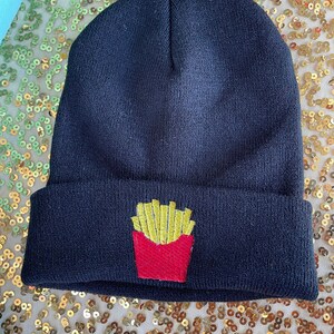 May include: Black knit beanie with a red and yellow embroidered french fry design.