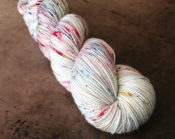 Coastside Sock Merino Hand Speckle Dyed Yarn in Pale Gray with Red, Blue and Gold