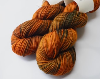May include: A skein of yarn in a deep orange and dark green colorway. The yarn is hand-dyed and has a variegated pattern.