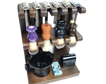 May include: A wooden shaving set organizer with six safety razors, four shaving brushes, a black shaving bowl, and a small box of Gillette blades. The organizer is made of dark wood and has a classic design.