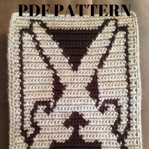 May include: A crocheted square with a brown and grey pattern of a dog's face. The text "PDF PATTERN" is at the top of the square and the text "Crafting For My Sanity" is at the bottom.