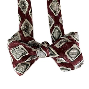 May include: A burgundy bow tie with a geometric pattern of white and gray diamonds.