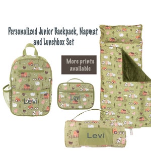 Puede incluir: Un juego personalizado de mochila junior, alfombra para siesta y lonchera. El juego presenta un fondo verde con un patrón de animales de granja. La mochila, la lonchera y la alfombra para siesta muestran el nombre "Levi". El texto "More prints available" también es visible.
