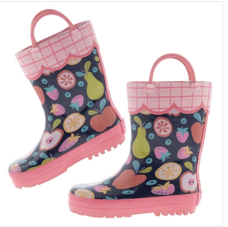 May include: A pair of navy blue rain boots featuring a colorful fruit pattern of apples, pears, strawberries, and orange slices. The boots have a pink scalloped trim with a grid pattern at the top, pink soles, and pink pull-on handles at the sides.