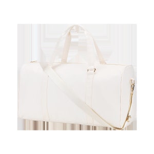 May include: A white canvas duffel bag with a long shoulder strap and gold accents.